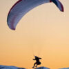 a person is parasailing in the mountains at sunset